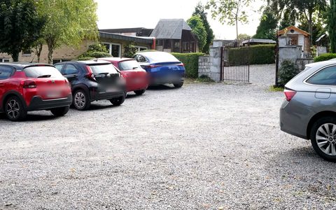 Vue du parking vers le bâtiment et le portail.