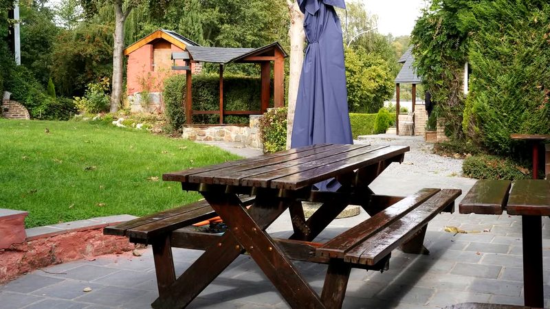 Le jardin de la salle Le Tremplin : pelouse, pergola et terrasse en pierre bleue.
